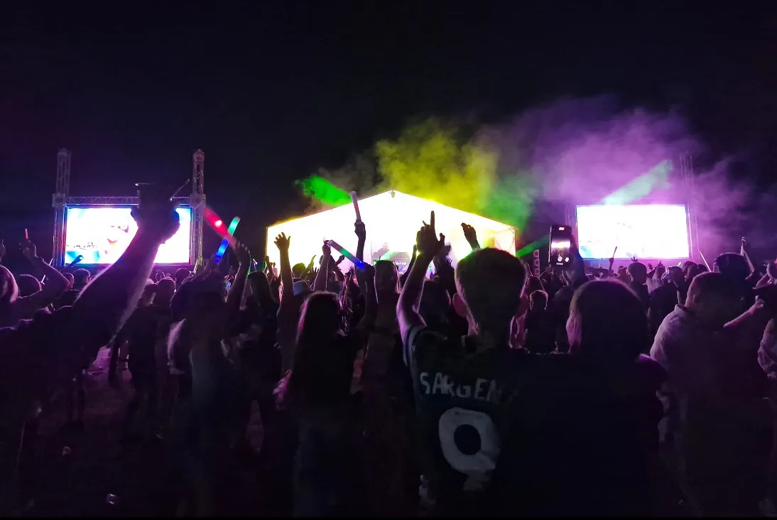 Festival crowd dancing in front of the DJ Paul Davies stage and laser light show